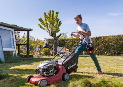 Die Familie hilft beim Rasen mähen